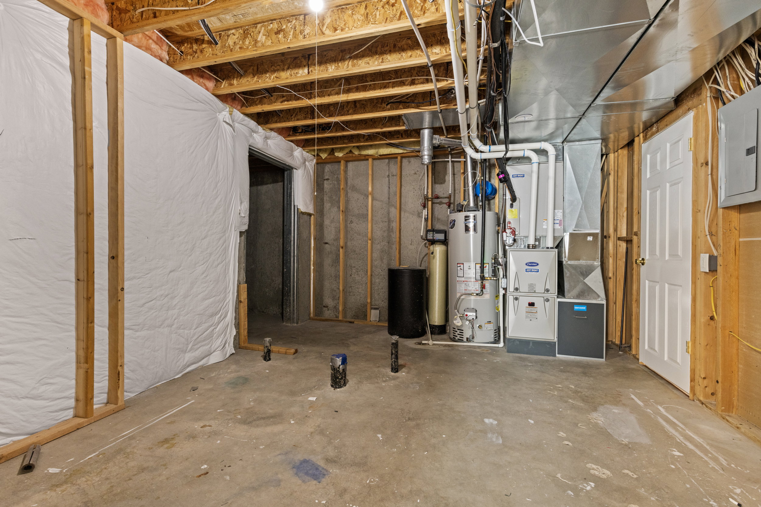 Unfinished basement space featuring exposed wood joists and concrete flooring