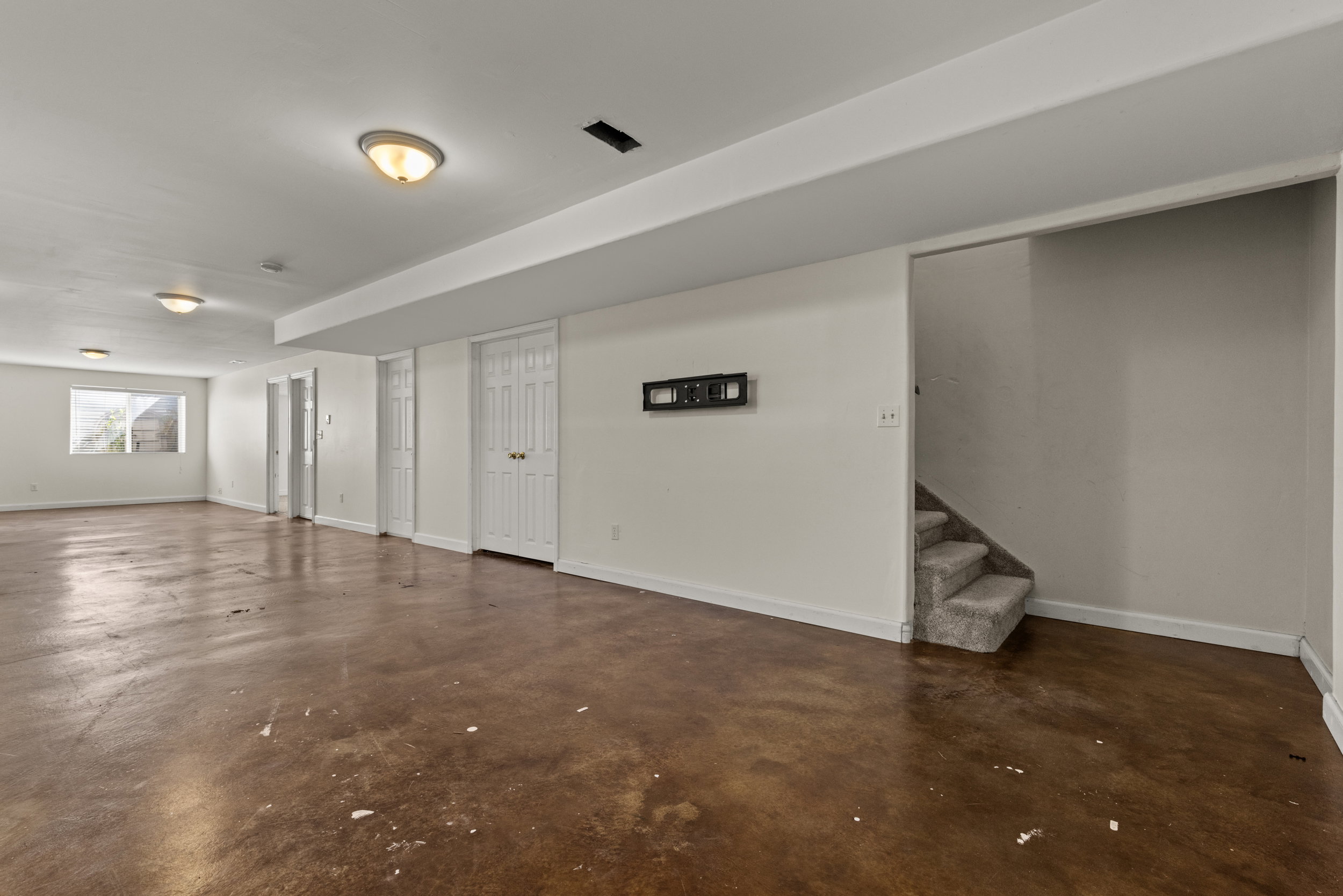 Expansive lower-level space featuring concrete flooring, white walls, and multiple white panel doors