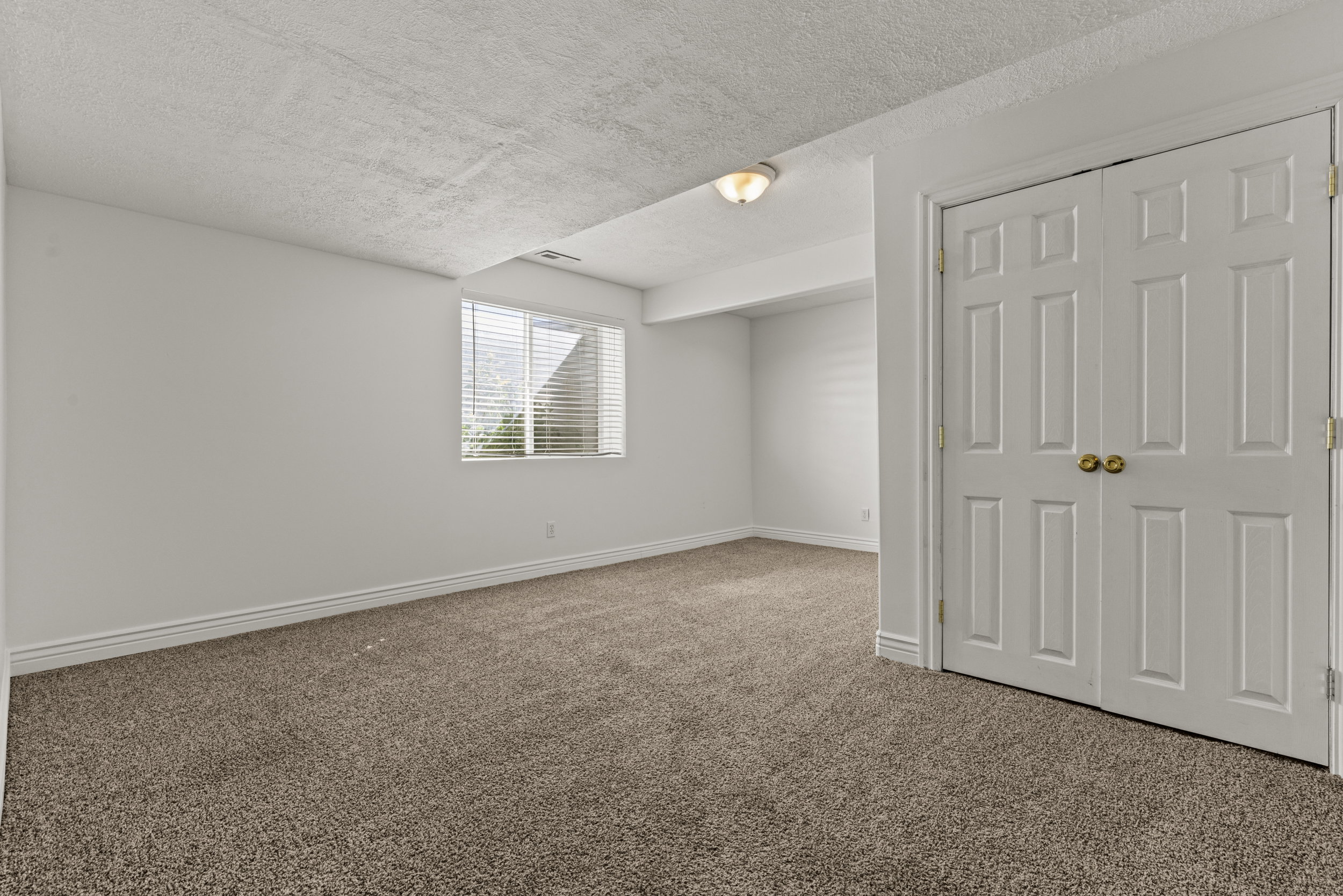 Carpeted room with white walls, baseboards, and textured ceiling