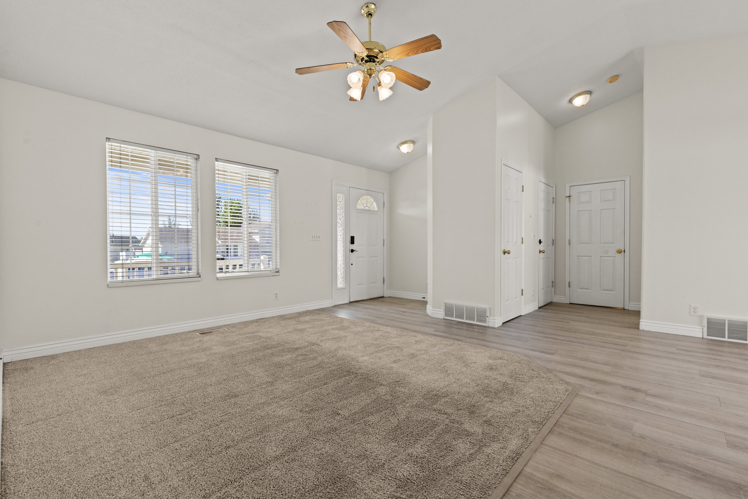 Vaulted ceilings enhance this living area featuring neutral carpet and wood-finish flooring