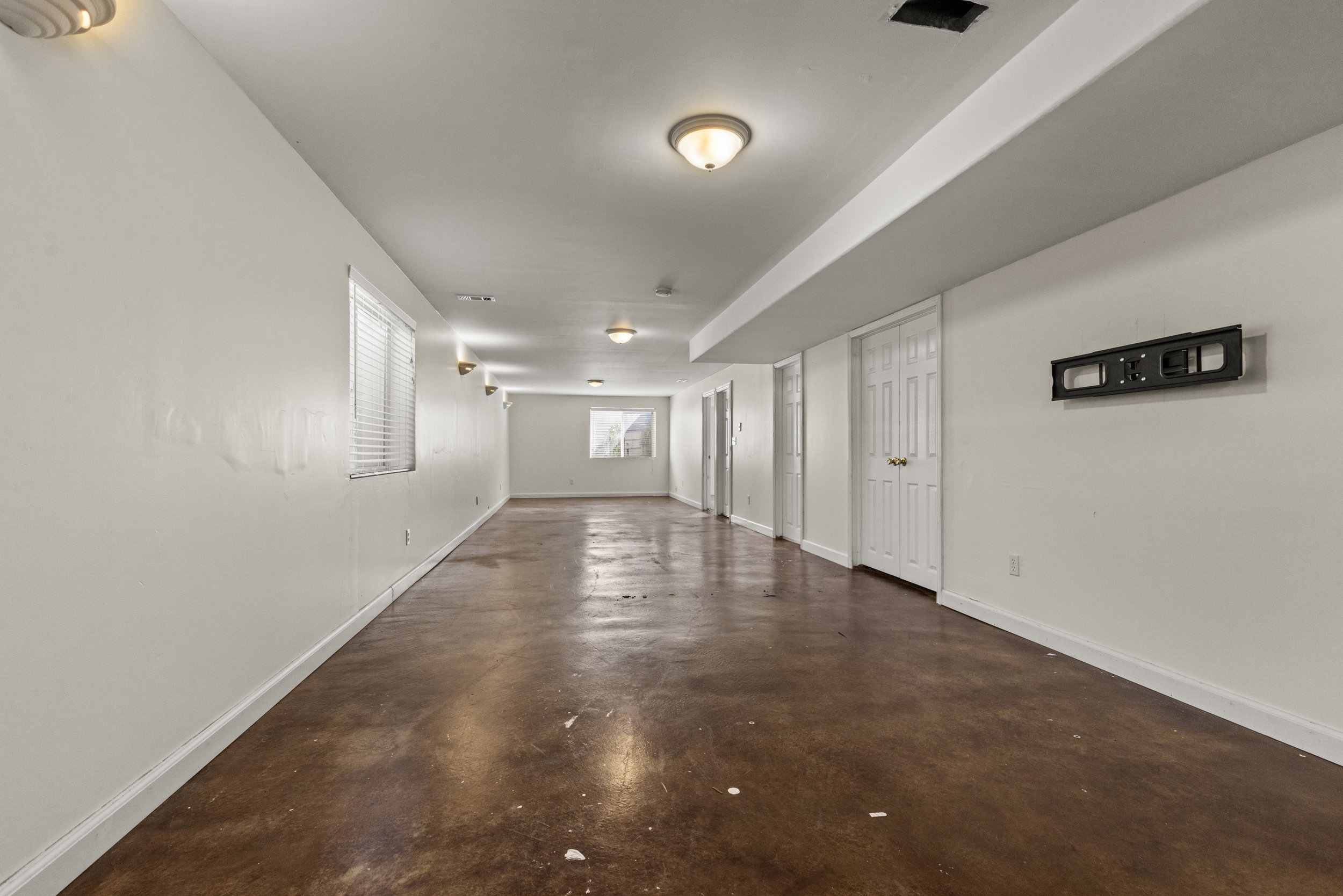 Expansive open finished space featuring polished concrete flooring, white walls, and multiple windows with blinds