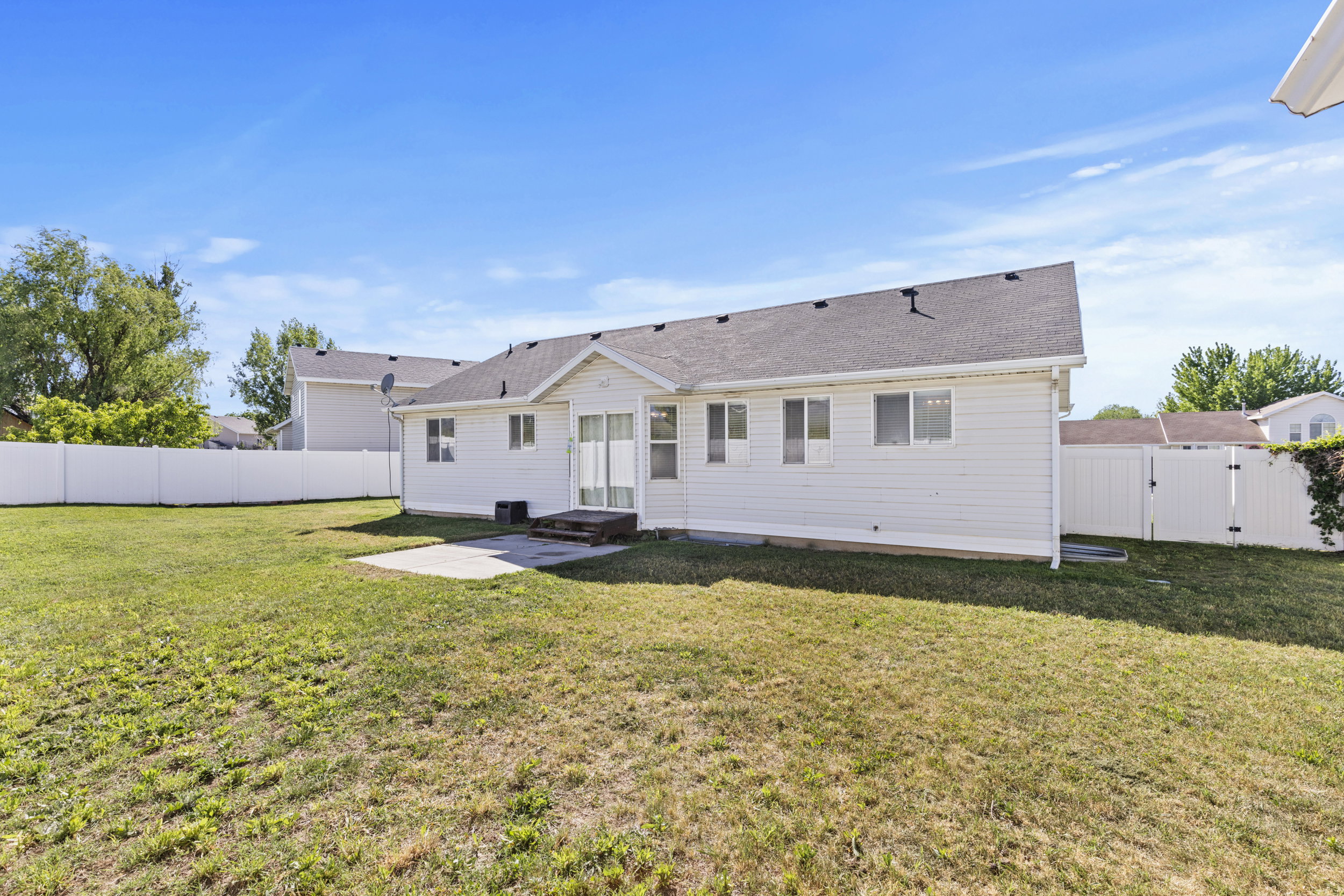 Rear exterior featuring white vinyl siding and a dark shingle roof