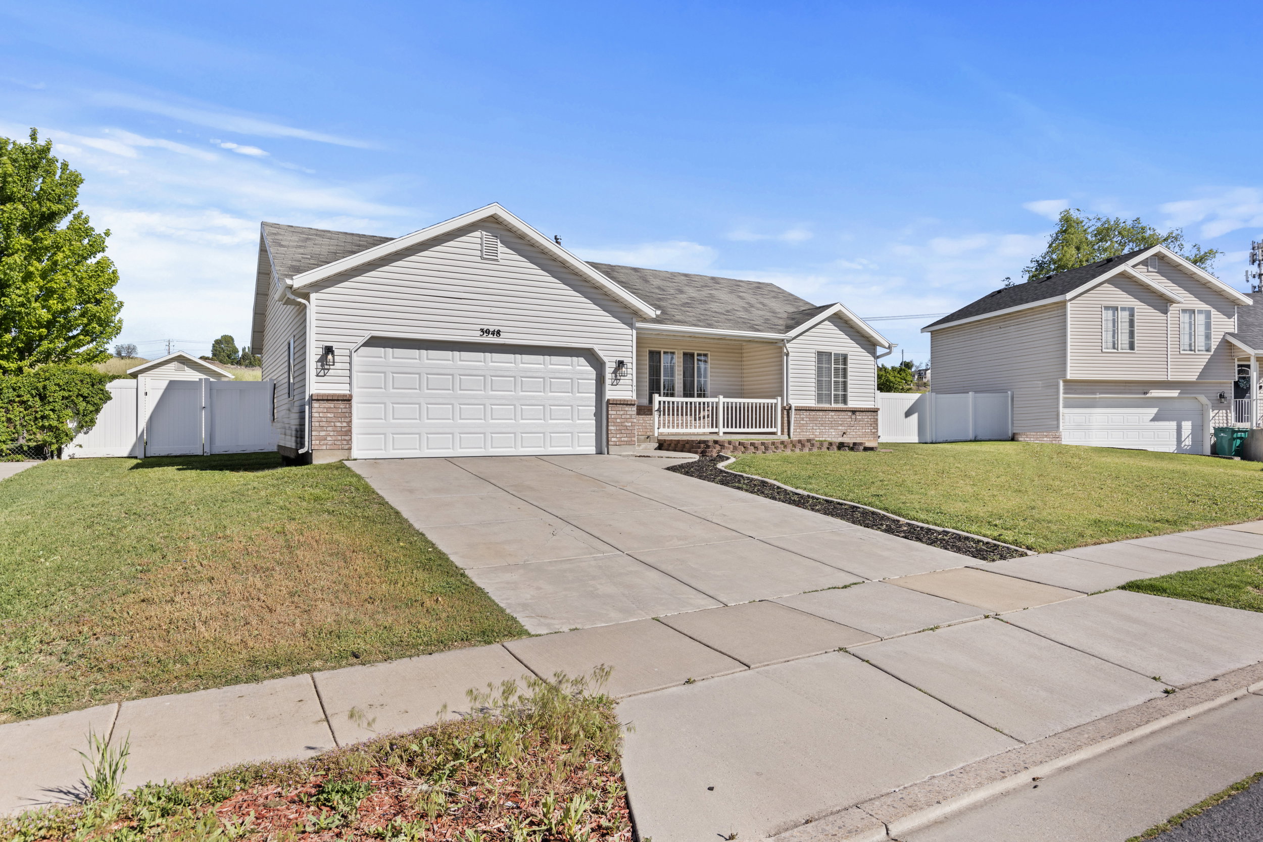 Ranch-style residence featuring a two-car garage, white siding, and a brick facade