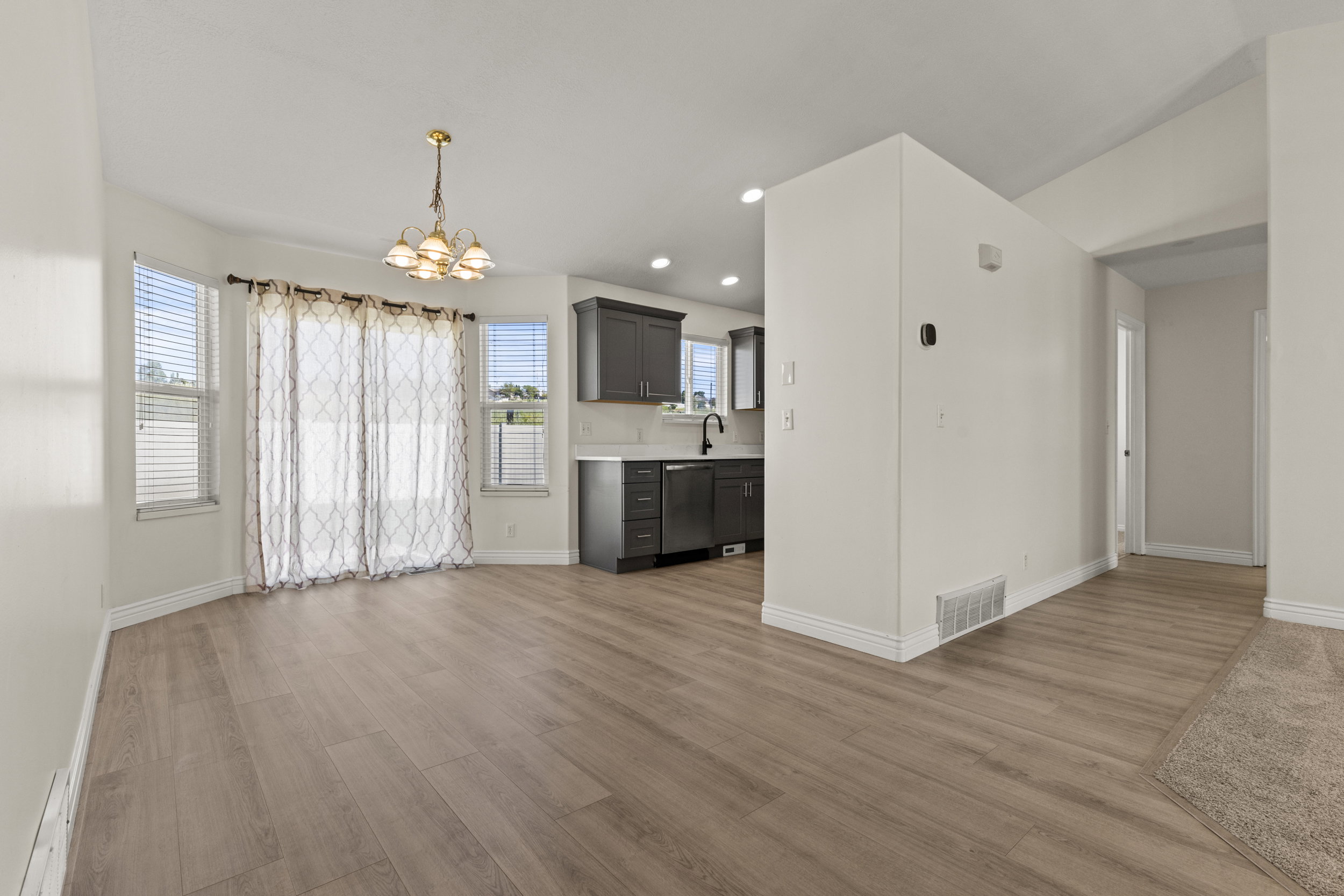 Dining area featuring wood-finish flooring, a contemporary chandelier, and a bay window with blinds