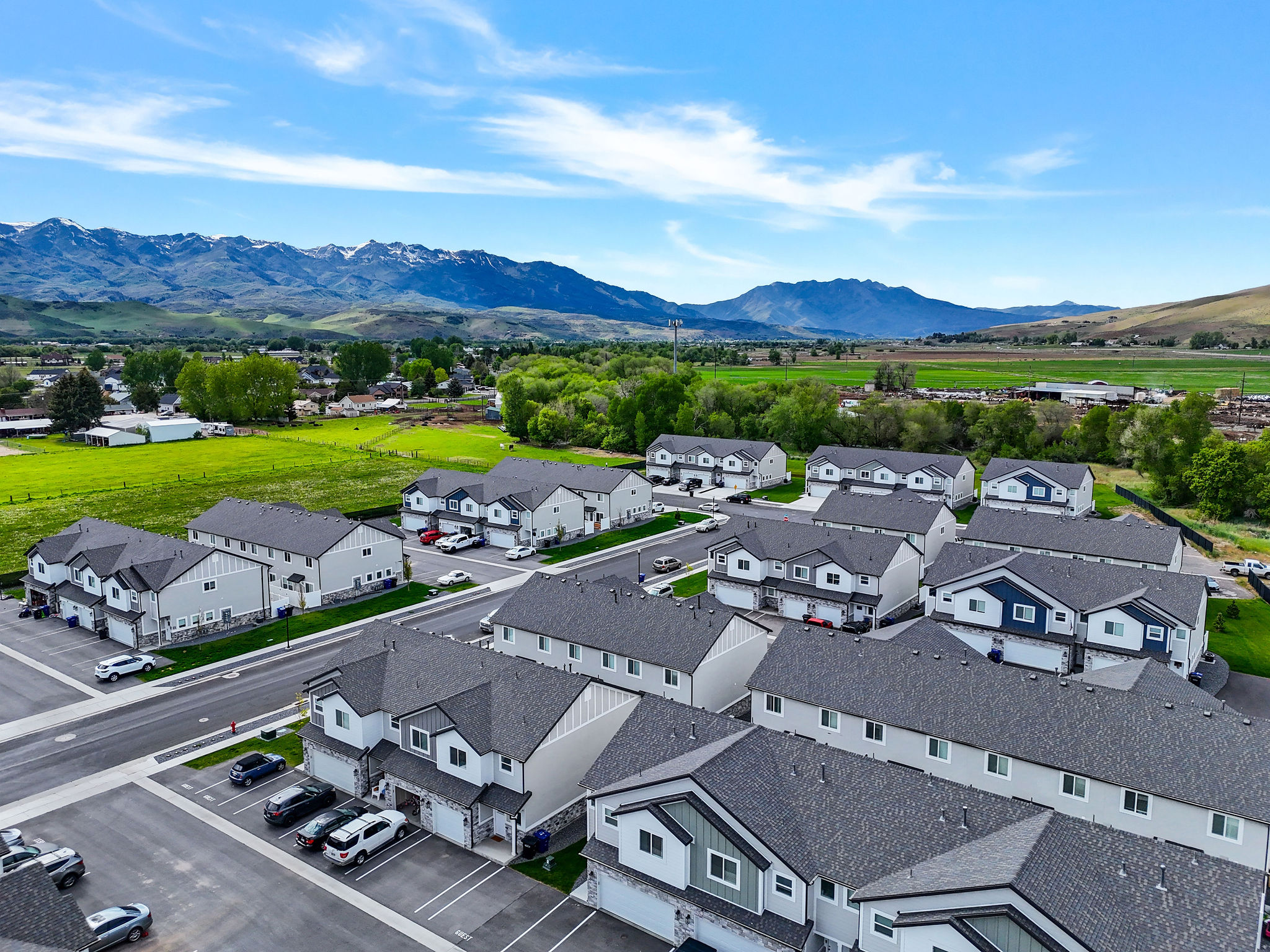New construction townhomes featuring varied exterior finishes, attached garages, and a paved streetscape