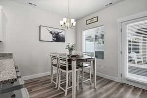 Light-filled dining area featuring wood-finish flooring, a contemporary chandelier, and a glass-paned door providing access to the exterior