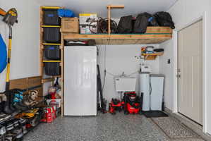 Garage featuring an epoxy-coated concrete floor, overhead storage shelving, a utility sink, and installed water filtration systems