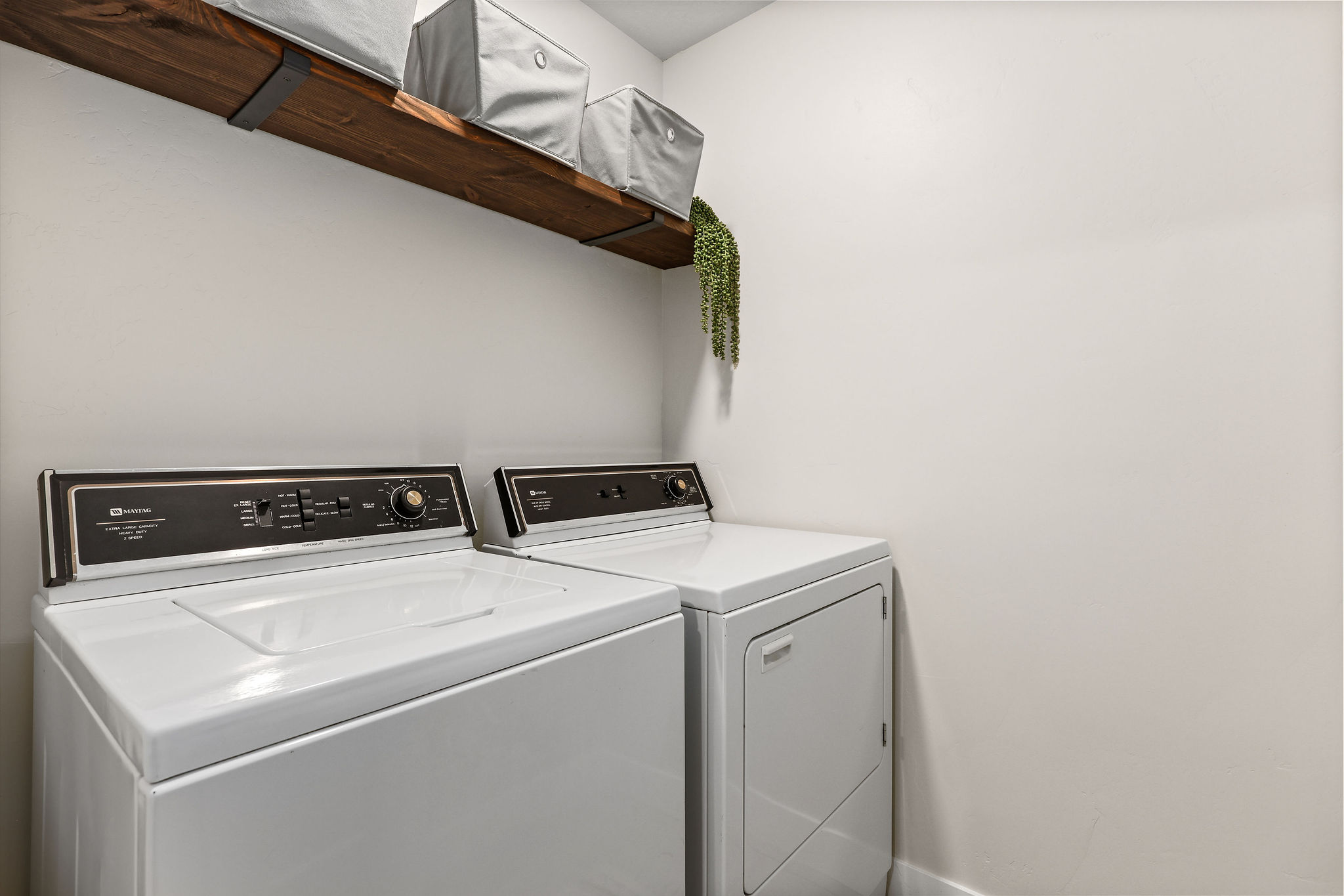 Dedicated laundry area featuring a wood-finish floating shelf with black metal brackets