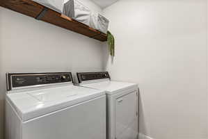 Dedicated laundry area featuring a wood-finish floating shelf with black metal brackets