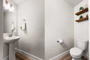 Pedestal sink with chrome faucet, wall-mounted mirror, and overhead vanity lighting