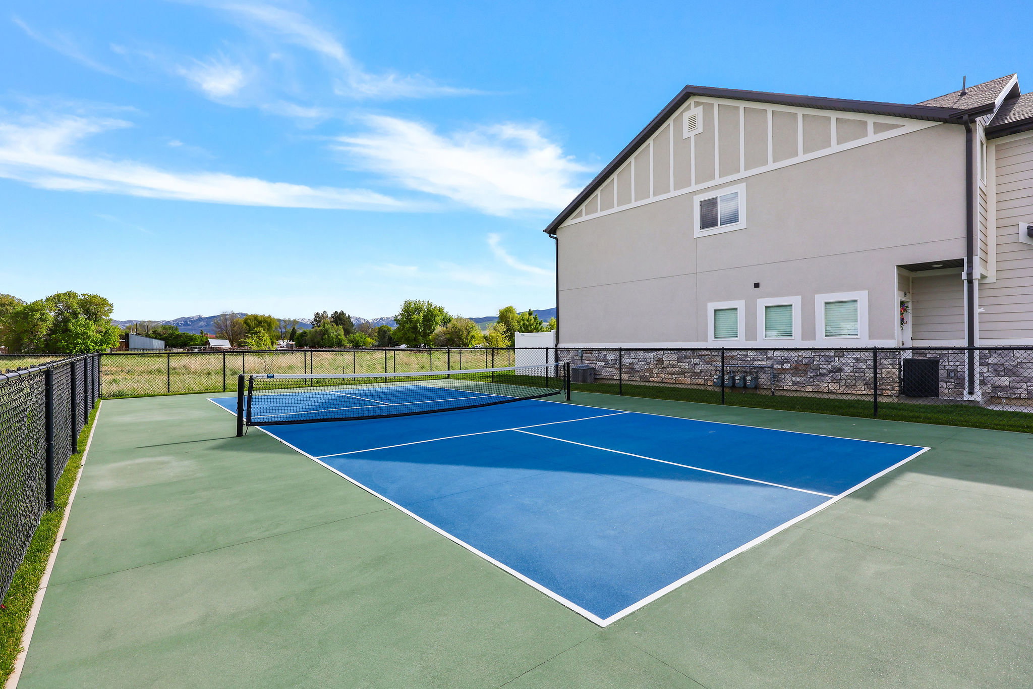 Outdoor court featuring a blue playing surface with white lines and a black net