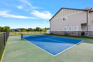 Outdoor court featuring a blue playing surface with white lines and a black net
