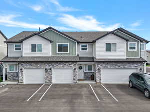 Modern townhome exterior featuring stone accents, light gray siding, and green vertical siding elements
