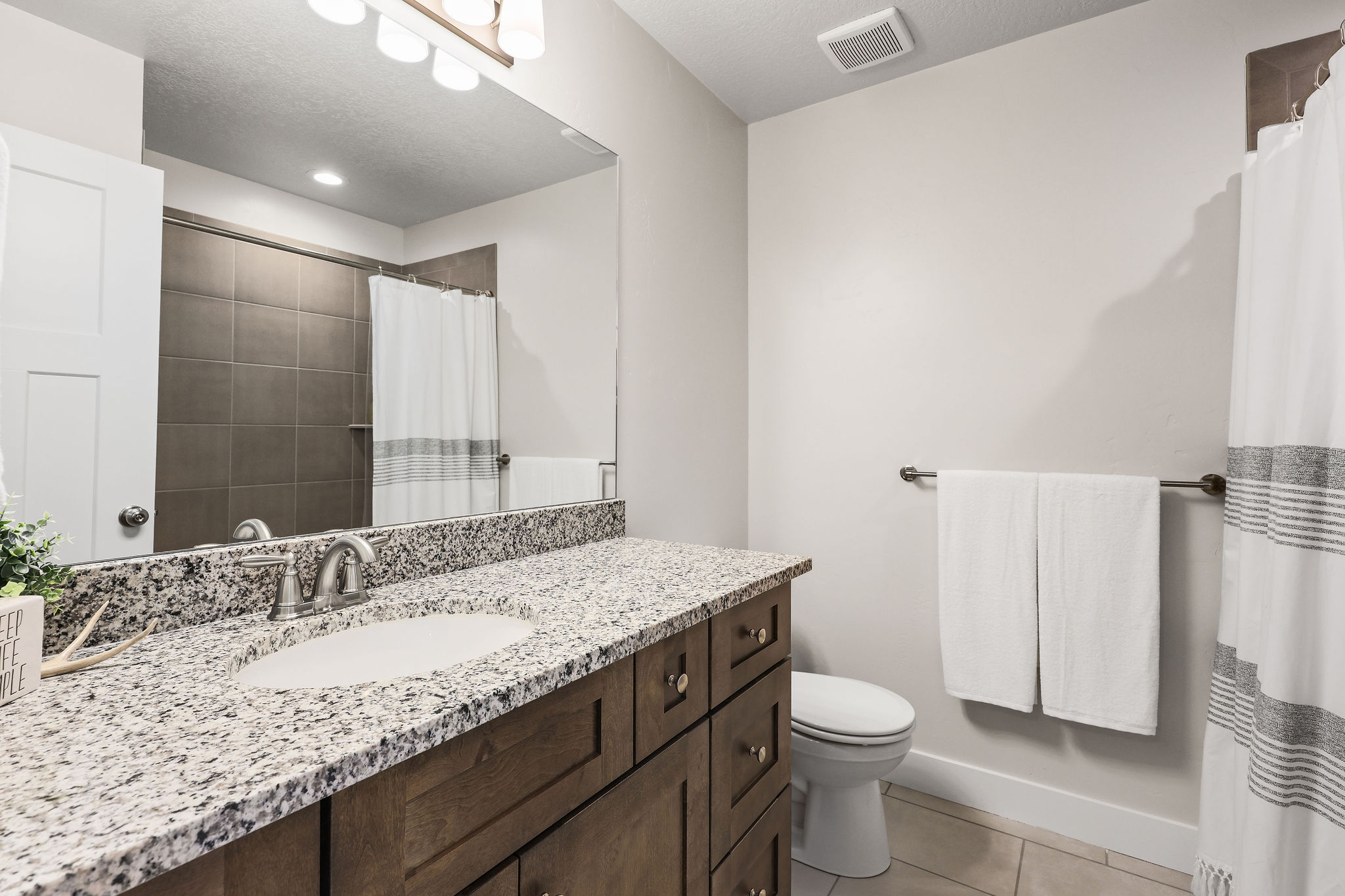 Bathroom featuring a granite countertop vanity with an undermount sink and a brushed nickel faucet