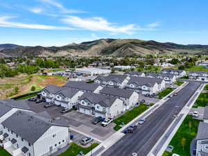 A collection of modern townhomes featuring light gray siding with dark gray gables, dark shingle roofing, and integrated garages, situated with a backdrop of distant mountains