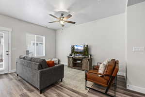Spacious living area featuring wood-finish flooring, a contemporary ceiling fan, and a glass-paneled exterior door
