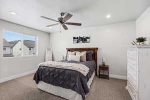 Neutral-toned bedroom featuring a ceiling fan with integrated lighting, recessed ceiling lights, and light-colored carpeting