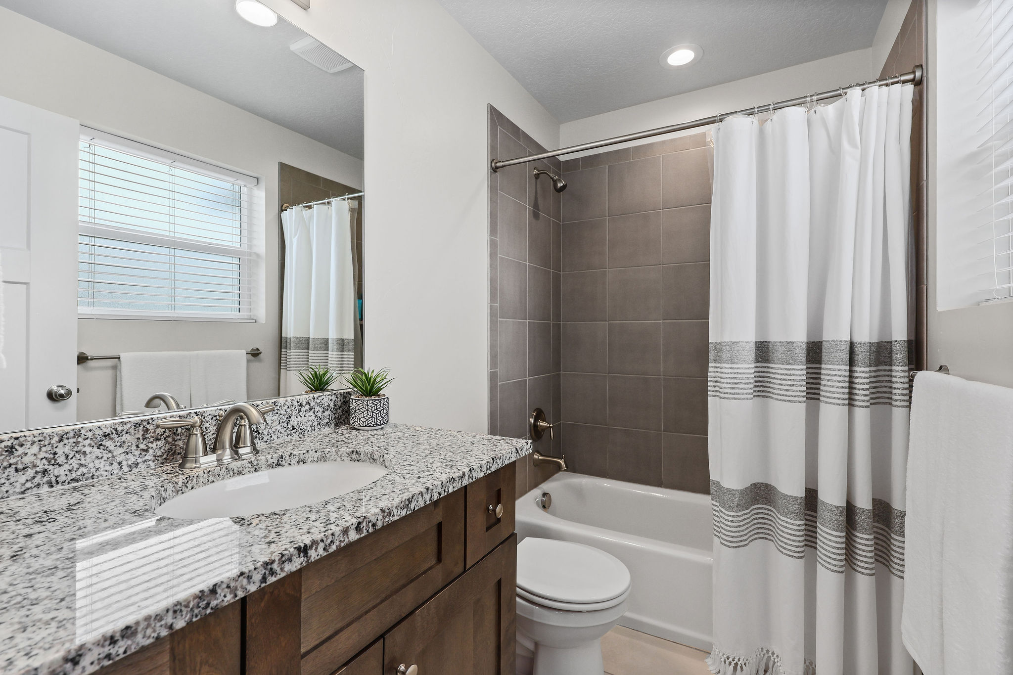 Bathroom featuring a dark wood-finish vanity with a granite countertop, undermount sink, and brushed nickel faucet