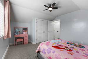 Carpeted bedroom featuring a sloped ceiling and a contemporary ceiling fan with integrated lighting