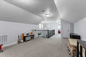 Spacious carpeted bonus room with sloped ceilings and recessed lighting