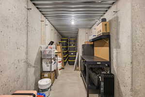 Concrete basement utility room featuring a corrugated metal ceiling and a built-in workbench with pegboard backing
