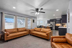 Open-concept living area featuring recessed lighting, a ceiling fan, and three large windows with blinds