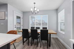 Dining area featuring wood-finish flooring, a contemporary chandelier, and ample natural light from multiple windows