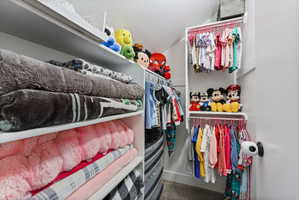 Walk-in closet featuring white shelving, multiple hanging rods, and a built-in chest of drawers