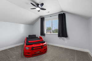 Room featuring a sloped ceiling, light gray wall tones, and gray carpet flooring