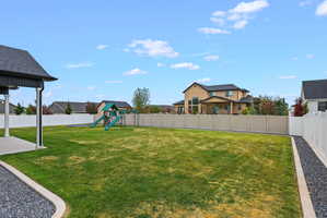 Expansive backyard featuring a manicured lawn, a large concrete patio, and a gravel border
