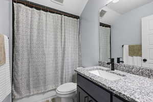Bathroom featuring a vanity with a light speckled countertop, an undermount sink, and a matte black faucet