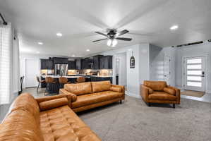 Open-concept living area with a kitchen island, dark cabinetry, and integrated recessed lighting