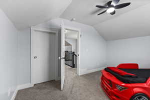 Room featuring a vaulted ceiling with a modern ceiling fan, gray carpet flooring, and light gray walls