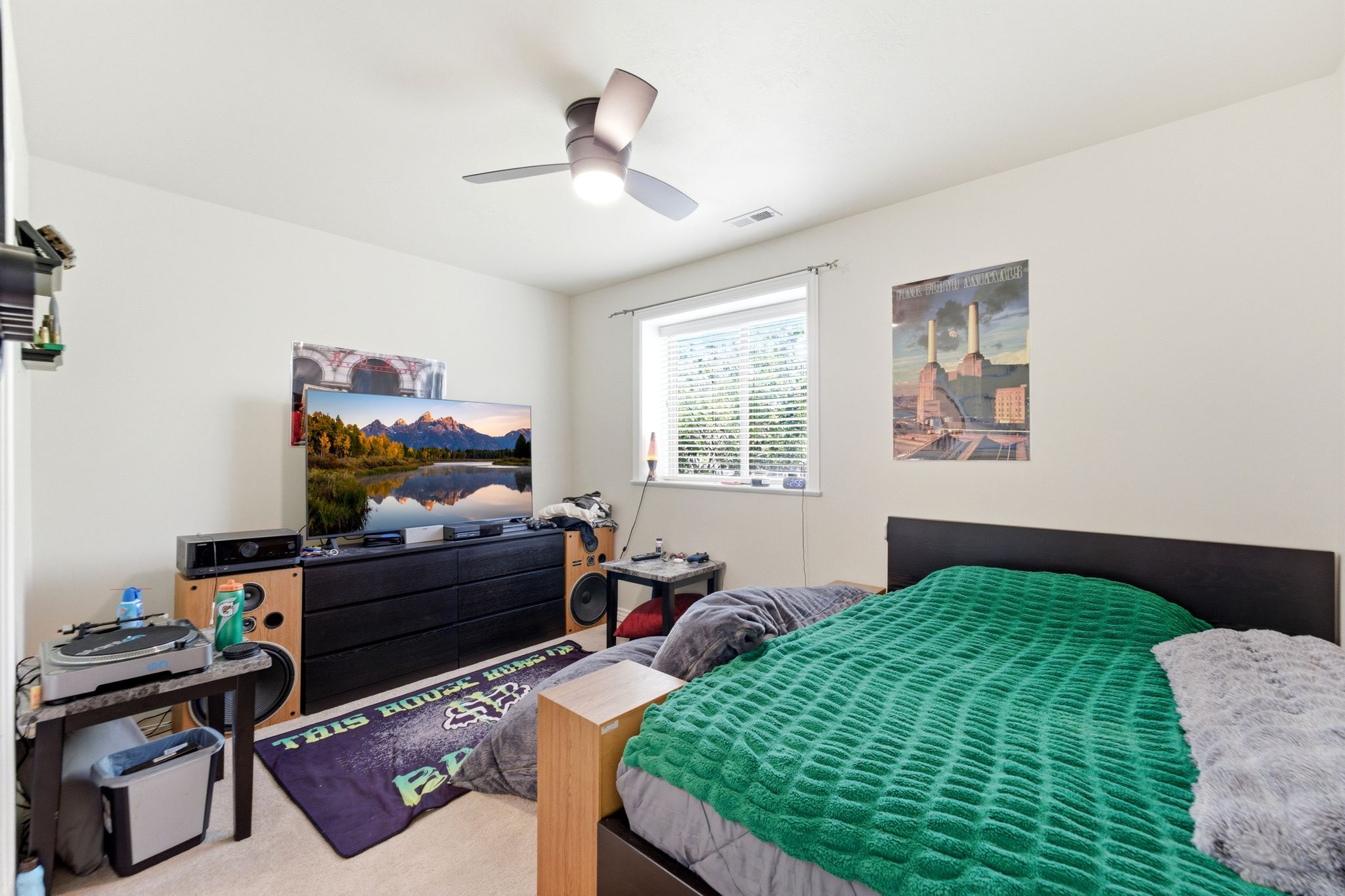 Carpeted room with a ceiling fan, white walls, and a window with blinds