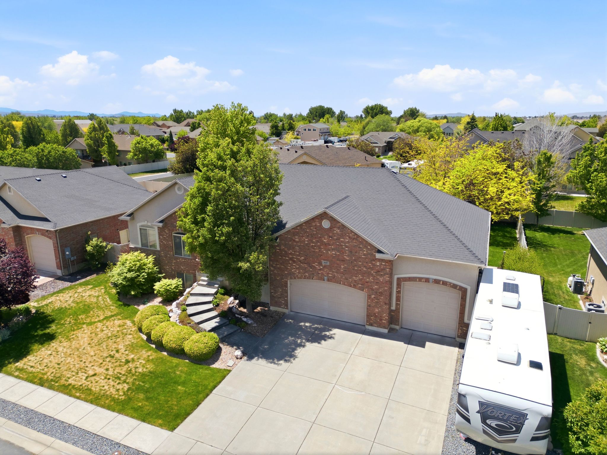 Brick and stucco exterior with a dark shingle roof
