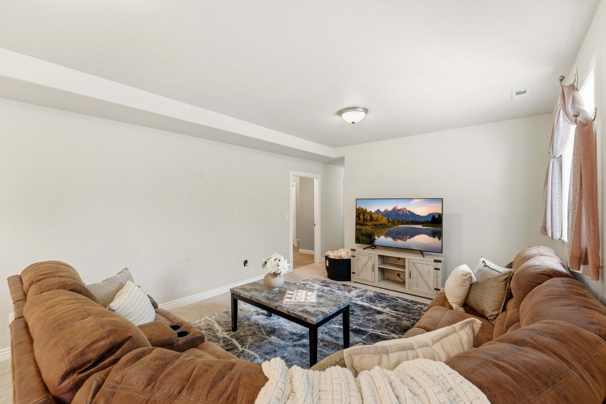 Spacious living area featuring light-colored walls and crown molding