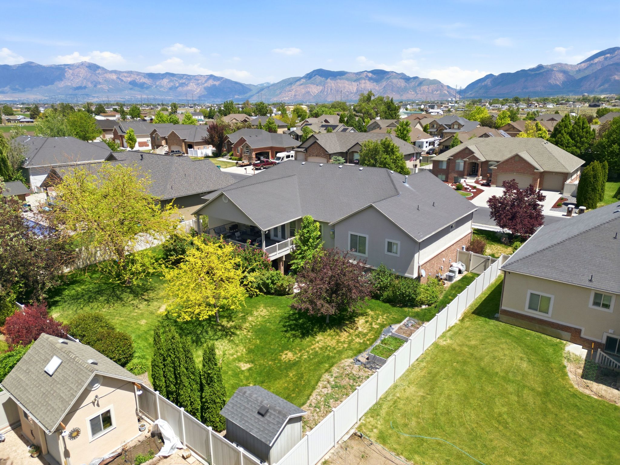 Expansive backyard featuring a manicured lawn, mature trees, and a mountain backdrop