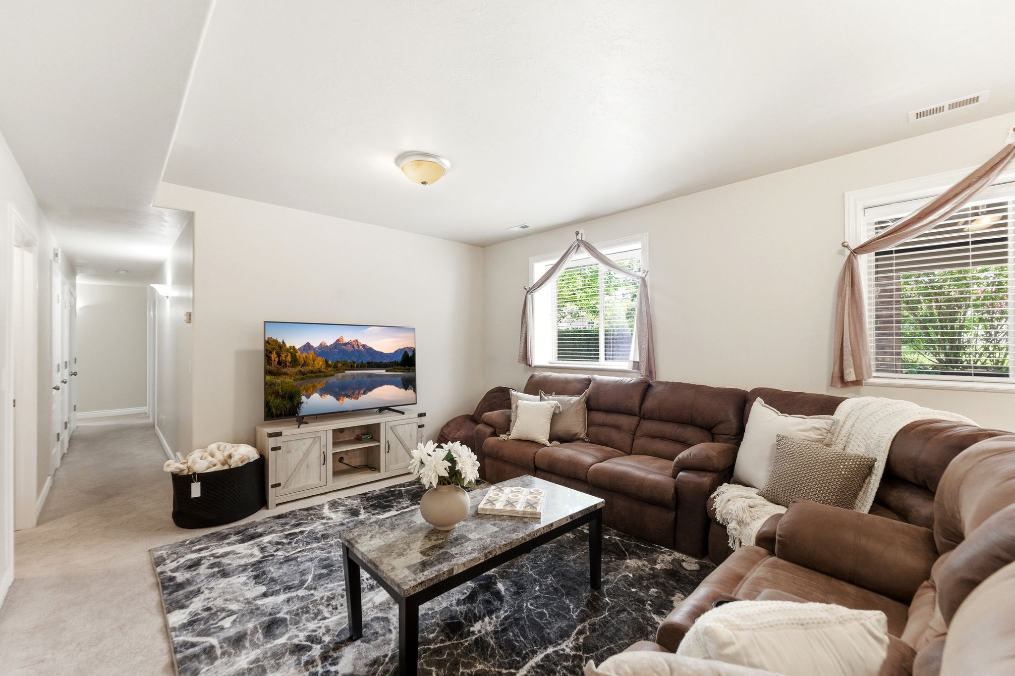 Spacious entertainment area featuring light-colored walls and recessed lighting
