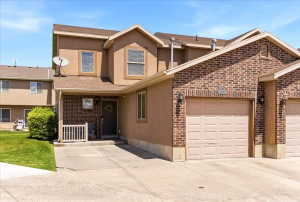 Exterior featuring a brick and stucco facade, an attached garage, a covered front porch, a concrete driveway, and a manicured lawn
