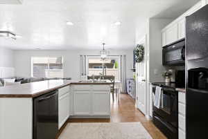 Open-concept kitchen featuring white cabinetry, a brown countertop, black appliances, and recessed lighting