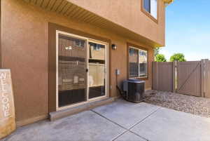 Exterior patio featuring concrete surfacing, a sliding glass door, and a brown privacy fence with a gate