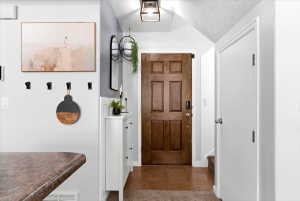 Entryway featuring a six-panel wood-finish door, tile flooring, and white trim