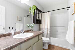 Bathroom featuring a single-sink vanity with a brown-toned countertop, a white drop-in basin, and a chrome faucet