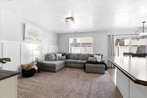 Carpeted living area featuring wainscoting, a flush mount ceiling light, and a window with blinds