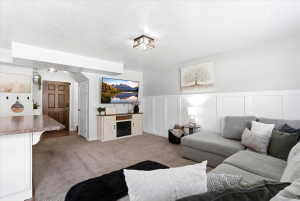 Spacious living area featuring neutral carpeting, a built-in entertainment console, and a wainscoting accent wall