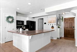 Kitchen island with a granite-style countertop, white cabinetry, and recessed lighting