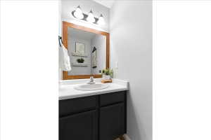 Vanity featuring a white countertop, undermount sink, and dark cabinetry