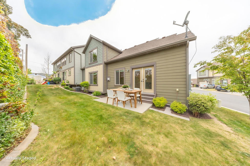 Rear exterior featuring horizontal siding in a neutral tone, double glass-paned doors, and a concrete patio