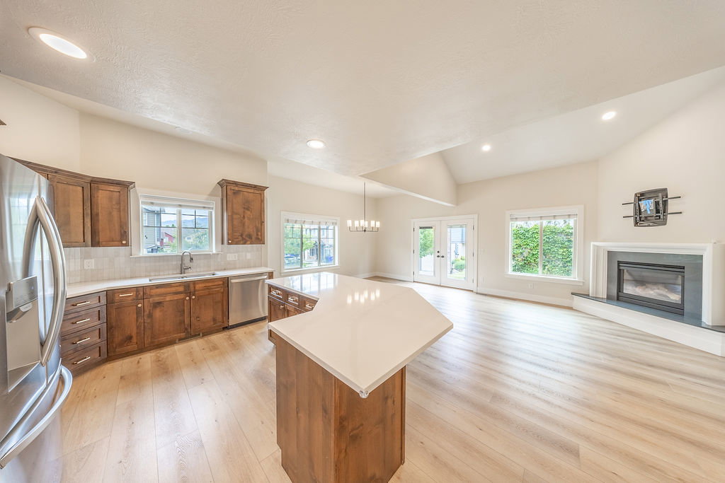 Open-concept living space featuring vaulted ceilings, light wood-finish flooring, and recessed lighting