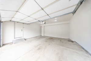 Spacious garage featuring a concrete floor, painted white walls, and a finished ceiling with exposed garage door track system
